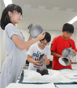 写真: 出土品を手に取る広報員 写真: 出土品を手に取る広報員