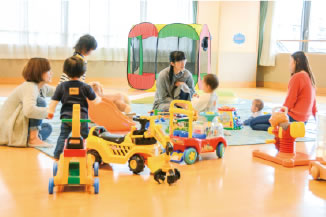 写真:たくさんの親子が集まり、おもちゃを囲んで一緒に楽しむ様子 写真:たくさんの親子が集まり、おもちゃを囲んで一緒に楽しむ様子