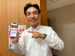 自分のスマートフォンで新ホームページを表示する石井市長